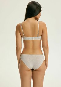 Jasnoszary zestaw biustonosza i majtek wykonany z miękkiego materiału, z regulowanymi ramiączkami, zapięciem na haftkę oraz gładką strukturą z minimalnymi detalami.