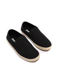 Czarne płócienne buty wsuwane z jutikowym podeszwą. Zaokrąglony czubek i elastyczne panele boczne dla łatwego zakładania. Płaska, teksturowana gumowa podeszwa.