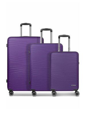 Trois valises violettes de tailles différentes avec des poignées télescopiques et quatre roues pivotantes, disposées côte à côte sur un fond blanc.