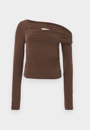 Brun langermet topp med asymmetrisk halslinje, samlet tekstur og tettsittende silhuett. Glatt stoff med subtil glans.