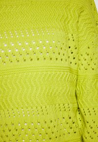 Maglione lavorato a maglia verde lime con un motivo a zigzag testurizzato e dettagli in occhio di pernice, con strisce orizzontali. Materiale morbido e traspirante.