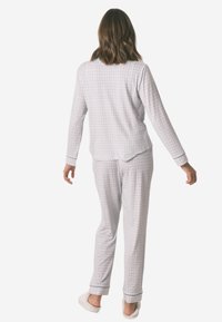 Szary i biały komplet piżamowy w kratkę, z długimi rękawami i spodniami w luźnym fasonie. Miękka tkanina z kontrastowymi mankietami.