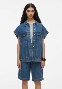 Denim pamatizgriezuma krekls ar īsām, platām piedurknēm, priekšējām pogām, kabatas detaļām, kombinēts ar saskaņotiem džinsu šortiem, zilā krāsā.
