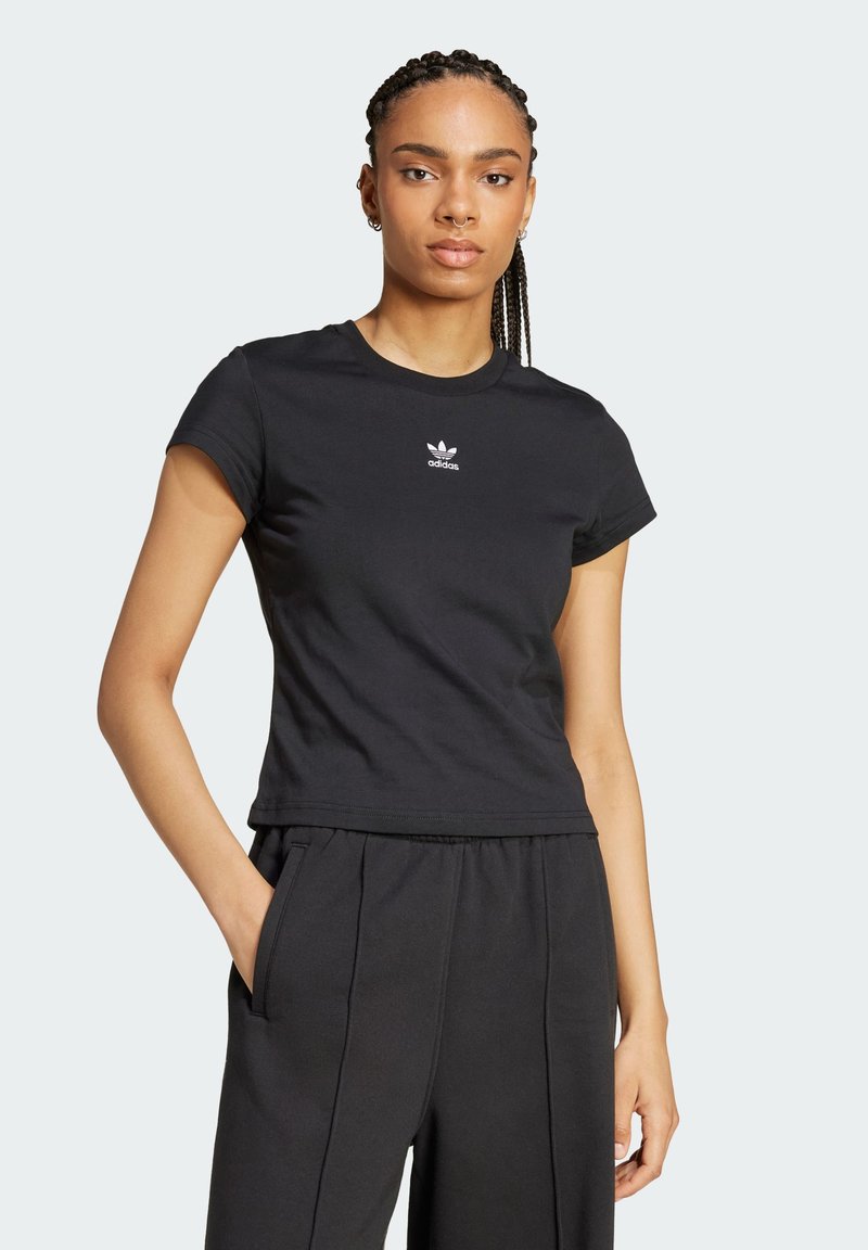 Tricou din bumbac negru cu mâneci scurte, guler rotund și logo-ul alb adidas pe piept. Stilizat cu pantaloni negri largi.