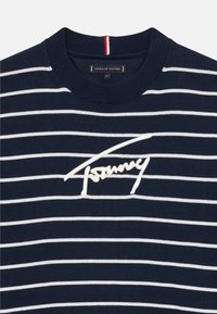 Maglione a righe blu navy con strisce orizzontali bianche, colletto a girocollo a coste e logo bianco ricamato al centro.