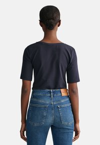 Mørkeblå bomulds T-shirt med korte ærmer, parret med medium-blå denim jeans med et lædermærkat på bagsiden.
