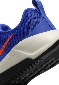 Blue athletic shoe featuring a textured mesh upper, orange accent, padded collar, and a contrasting white midsole with a black rubber outsole.