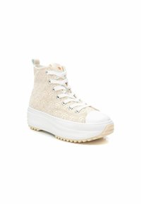 Zapatillas altas con una parte superior de tela beige texturizada, suela de goma blanca y punta redonda. Presentan ojales de metal y un bucle en la parte trasera.