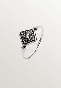 Anillo de plata en forma cuadrada con un incrustación de piedra en blanco y negro, que presenta una piedra central transparente y dos pequeñas piedras de acento en la banda.