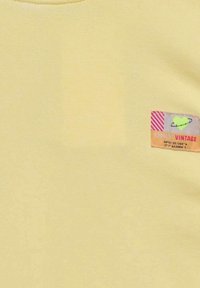 T-shirt en coton jaune à col rond et petite étiquette multicolore avec le texte et des graphiques "ONLY VINTAGE".