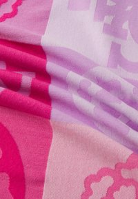 Tessuto con sfumature di rosa e lavanda caratterizzato da un motivo floreale ripetitivo, texture morbida e pieghe drappeggiate che mostrano transizioni di colore.