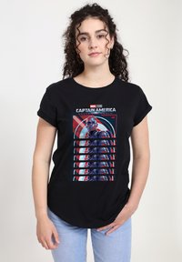 Camiseta negra con un estampado gráfico de Capitán América en colores vibrantes, detallando el personaje y el texto, sobre una suave tela de algodón.
