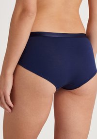 Marineblauwe katoenen hipsteronderbroek met een soepele tailleband en een bescheiden achterzijde, met een zachte textuur zonder zichtbare naden.