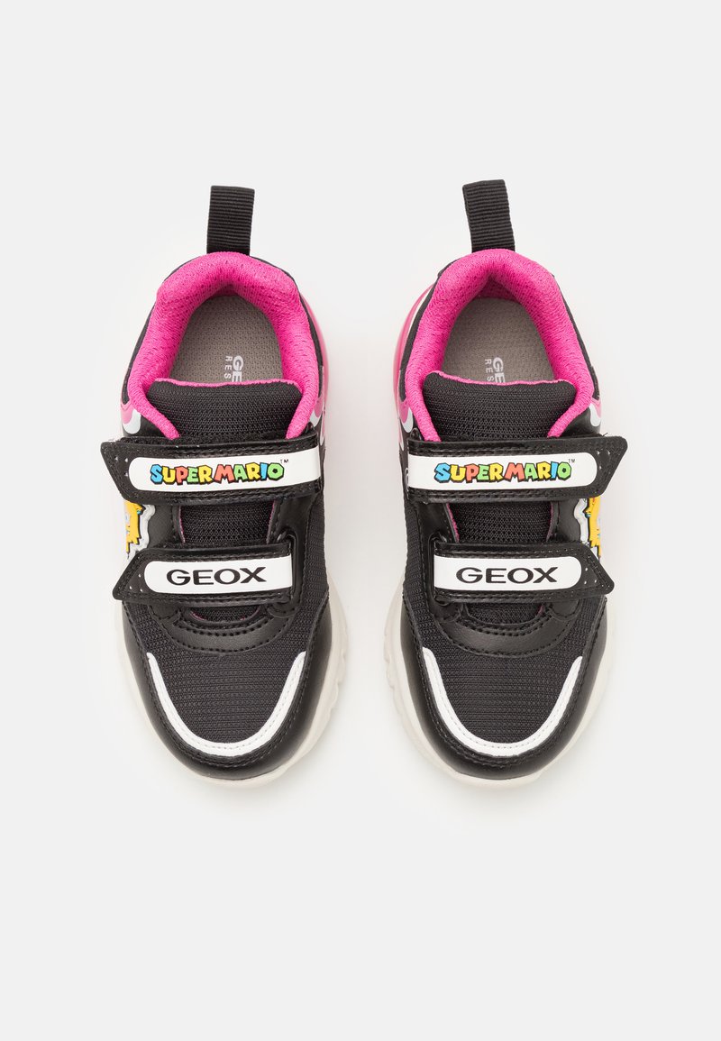 Zapatillas negras con acentos en rosa, que cuentan con una parte superior de malla suave, correas de Velcro y gráficos de "Super Mario" en una etiqueta blanca.