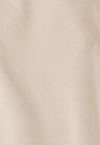 Tissu beige avec une texture lisse et un motif subtil en losange. Légèrement drapé, mettant en valeur ses qualités douces et flexibles.