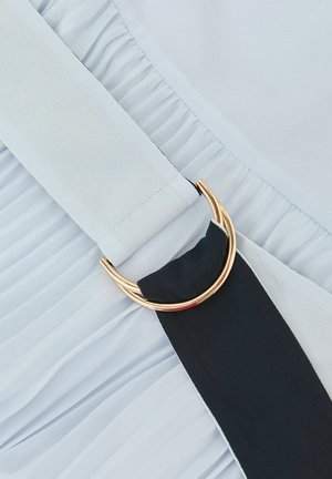 Tessuto azzurro chiaro plissettato con una banda nera a contrasto decorata da una fibbia circolare dorata. Texture liscia e dettagli di design a strati.