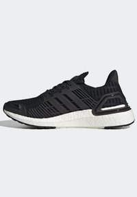 Baskets de sport noires avec empeigne en maille, détails cage en plastique, cinq bandes latérales et semelle épaisse blanche texturée.