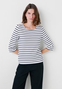 Top a strisce bianche con righe orizzontali navy, maniche a tre quarti, scollatura rotonda e bottoni decorativi sulle spalle.