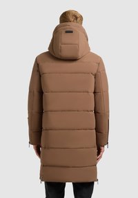Brun vadderad parka med en strukturerad huva, horisontellt quiltat mönster, sidodragkedjor och en slät yta.