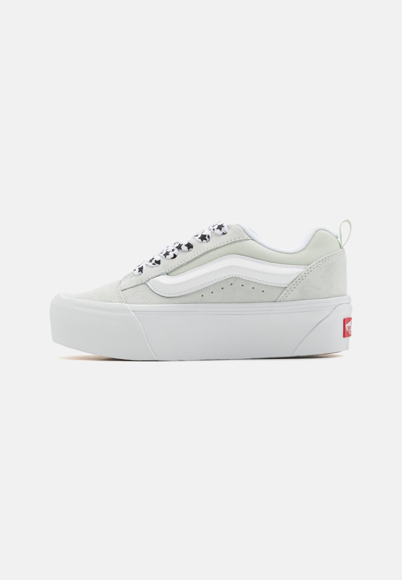 Sneaker in suede grigio chiaro con accenti bianchi, suola spessa bianca, lacci a motivo in bianco e nero e linguetta sul tallone posteriore con logo rosso.