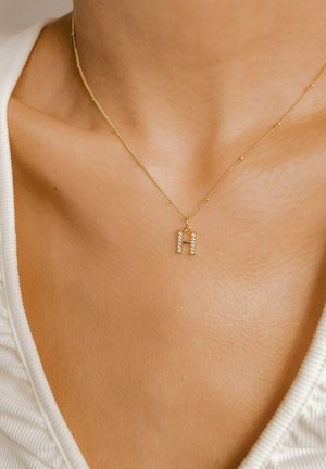 Goldkette mit einem Anhänger in Blockbuchstaben "H", der mit klaren Strasssteinen verziert ist, und durch ein zartes Design und reflektierende Textur hervorsticht.