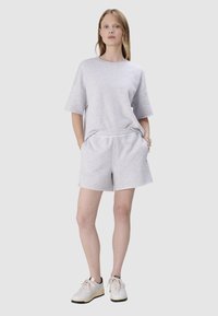 Szara koszulka z krótkim rękawem i dopasowane szorty, wykonane z miękkiego materiału. Koszulka ma luźny krój, a szorty mają elastyczny pas.