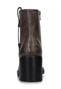 Stivale alla caviglia in pelle marrone con finitura testurizzata, tacco impilato nero e cerniera laterale. Presenta un anello per facilitare l'indossamento.