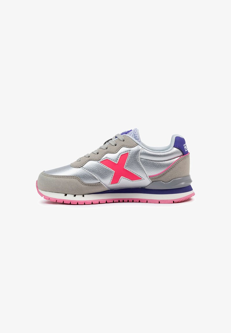 Zapatilla plateada y gris con acentos rosas, materiales de ante y malla, punta redonda, suela de goma en contraste, con un gran logo rosa.