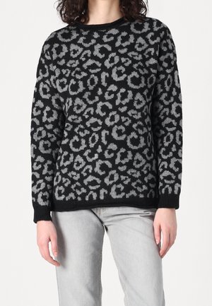 Langærmet sweater med sort og gråt leopardmønster, båret med lysegrå jeans, korte ved halsen og midt på låret.