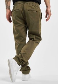 Pantaloni cargo verde oliva con vestibilità comoda, cintura elastica e due tasche posteriori. Abbinati a sneakers bianche.