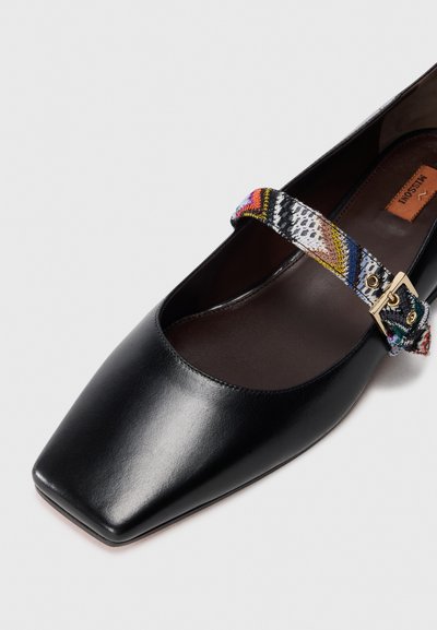 Black leather shoe with a square toe. Features a multicolored fabric strap with a gold buckle, showcasing a textured pattern.