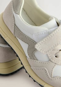 Lichtgrijze suède sportschoenen met witte meshpanelen, voorzien van klittenbandsluitingen, gestructureerde rubberen zolen en minimale stiksel details.