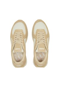 Pár béžových tenisek Puma se zamkovým a síťovým detailem, zavázané tkaničky, pohled shora na bílém pozadí.