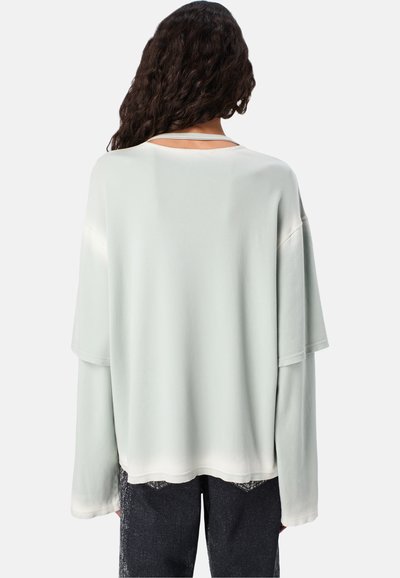 Lichtgroene oversized sweatshirt met verlaagde schouders, met een gladde textuur en een ronde halslijn, weergegeven van achteren.