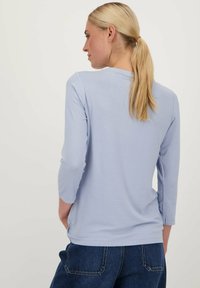 Lichtblauwe longsleeve shirt van een zachte, gladde stof. Heeft een ronde halslijn en driekwart mouwen. Casual pasvorm met een eenvoudig ontwerp.