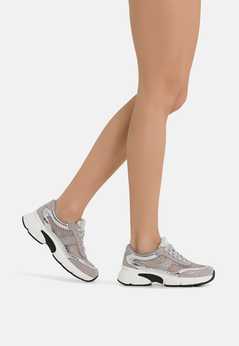 Sporty sneakers with a mesh upper in gray and silver, padded tongue, white midsole, and black outsole. Feature laces and a textured design.