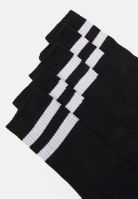 Black socks featuring three horizontal white stripes near the top. Made of a woven fabric with ribbed texture, designed for comfort.