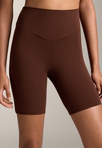 barna, magas derékvonallal készült kerékpáros nadrág, sima, rugalmas anyagból. A dizájn karcsú, illeszkedő sziluettel és minimális varrási részletekkel rendelkezik.