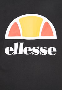 Camiseta negra con un gráfico central que presenta un semicírculo amarillo y acentos rojos sobre el nombre de la marca "ellesse" en letras blancas en negrita.