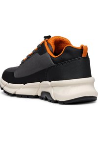 Zapatilla deportiva negra y gris con un interior naranja, que presenta una parte superior texturizada, un cuello acolchado y una suela de amortiguación blanca.