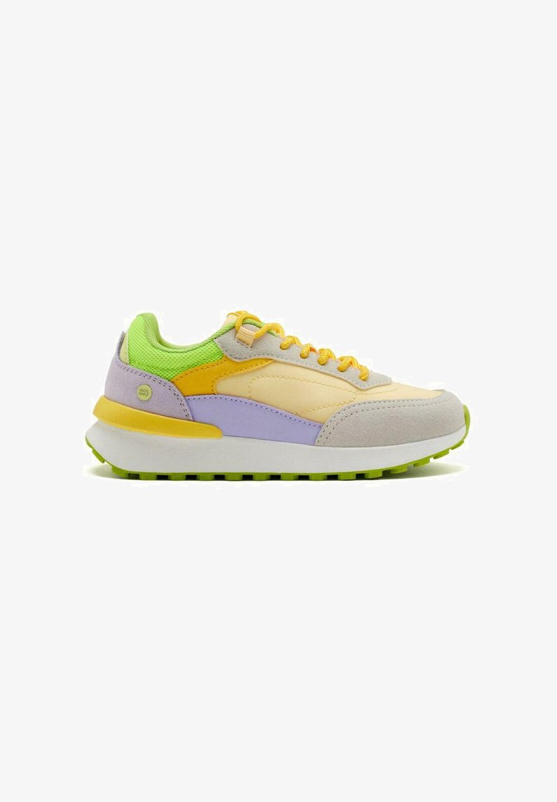 Zapatillas deportivas con una mezcla de materiales que incluyen ante y malla; los colores incluyen amarillo, verde, púrpura y beige. Suela blanca gruesa con acentos verdes.