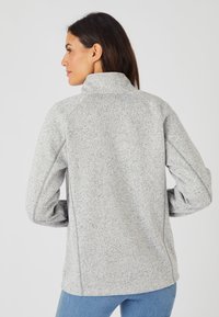 Giacca grigia con zip e colletto alto, polsini a costine e tessuto morbido e testurizzato. Presenta maniche raglan e un design dal fit rilassato.