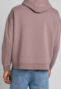 Oversized hooded sweatshirt in dusty pink, featuring ribbed cuffs and hem, made of soft jersey fabric with a smooth texture.