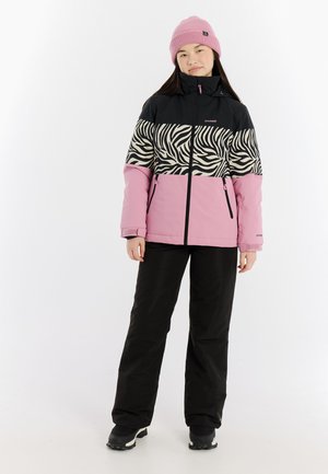 Farbige Winterjacke mit einem schwarzen Oberteil, einem Zebra-Muster im Mittelteil und einem pinken unteren Abschnitt. Kombiniert mit schwarzen Hosen und einer pinken Mütze.