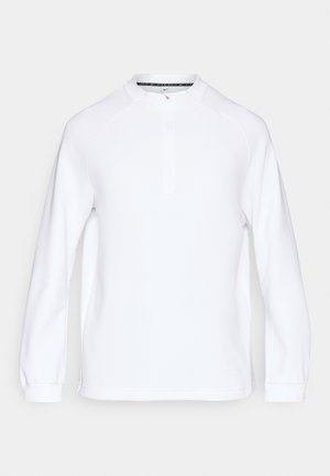 Vit långärmad pullover med hög krage och halv dragkedja, med ribbad textur och raglanärmar för rörelsefrihet.