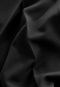 Schwarzer Stoff, glatte Textur mit sichtbaren Falten und Knicken, die ein mattes Finish zeigen. Keine Muster oder Akzente vorhanden.