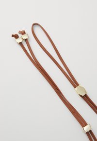 Brown leather straps with gold metallic accents. Features two ends with rectangular gold hardware and a smooth texture. Designed for durability.