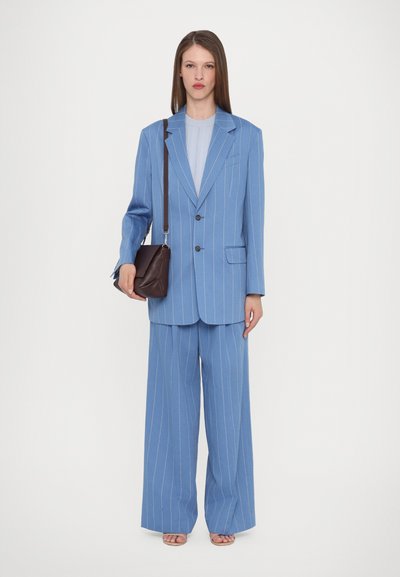 Light blue pinstripe suit jacket and wide-leg trousers with a soft texture, paired with a small dark brown crossbody bag.