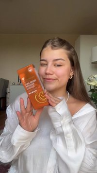 Esencja ślimaka Snail Repair w pomarańczowym opakowaniu, z ilustracją ślimaka. Modelka w białej satynowej bluzce trzyma produkt na neutralnym tle.