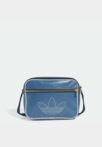 Blå faux läder crossbody-väska med vit piping, framsidans dragkedjefack och präglad logotyp. Har justerbar axelrem och strukturerade sidor.